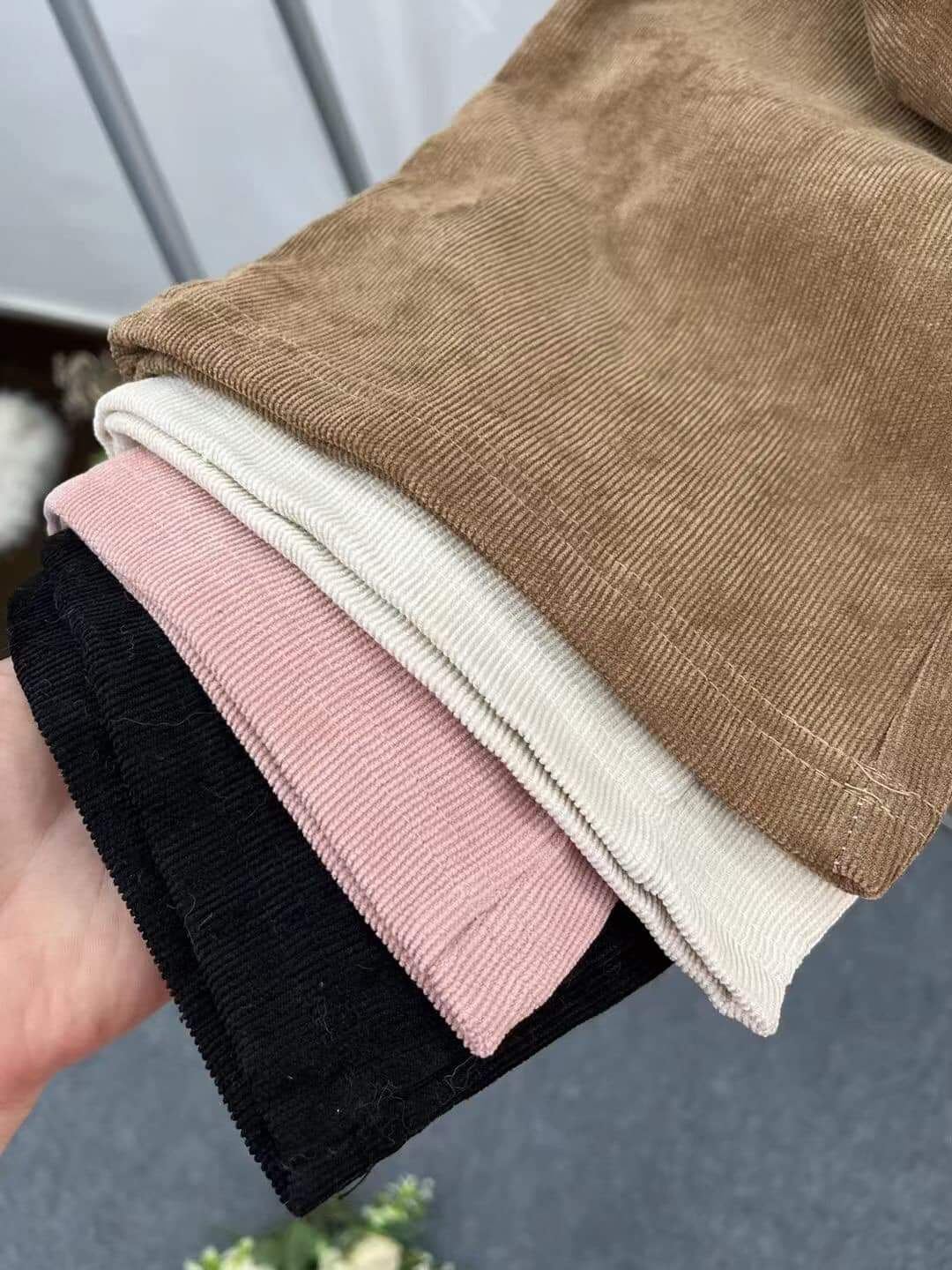 Stack of folded corduroy fabric in tan, white, pink and black