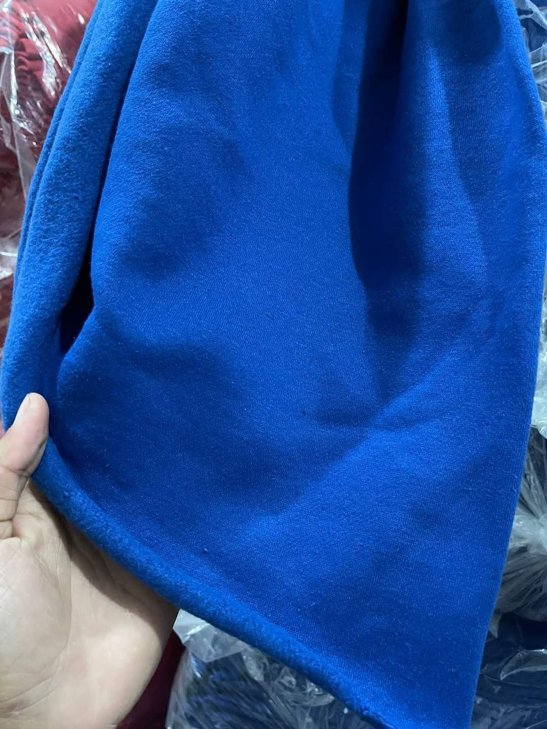 Close-up of blue fabric roll being inspected by hand